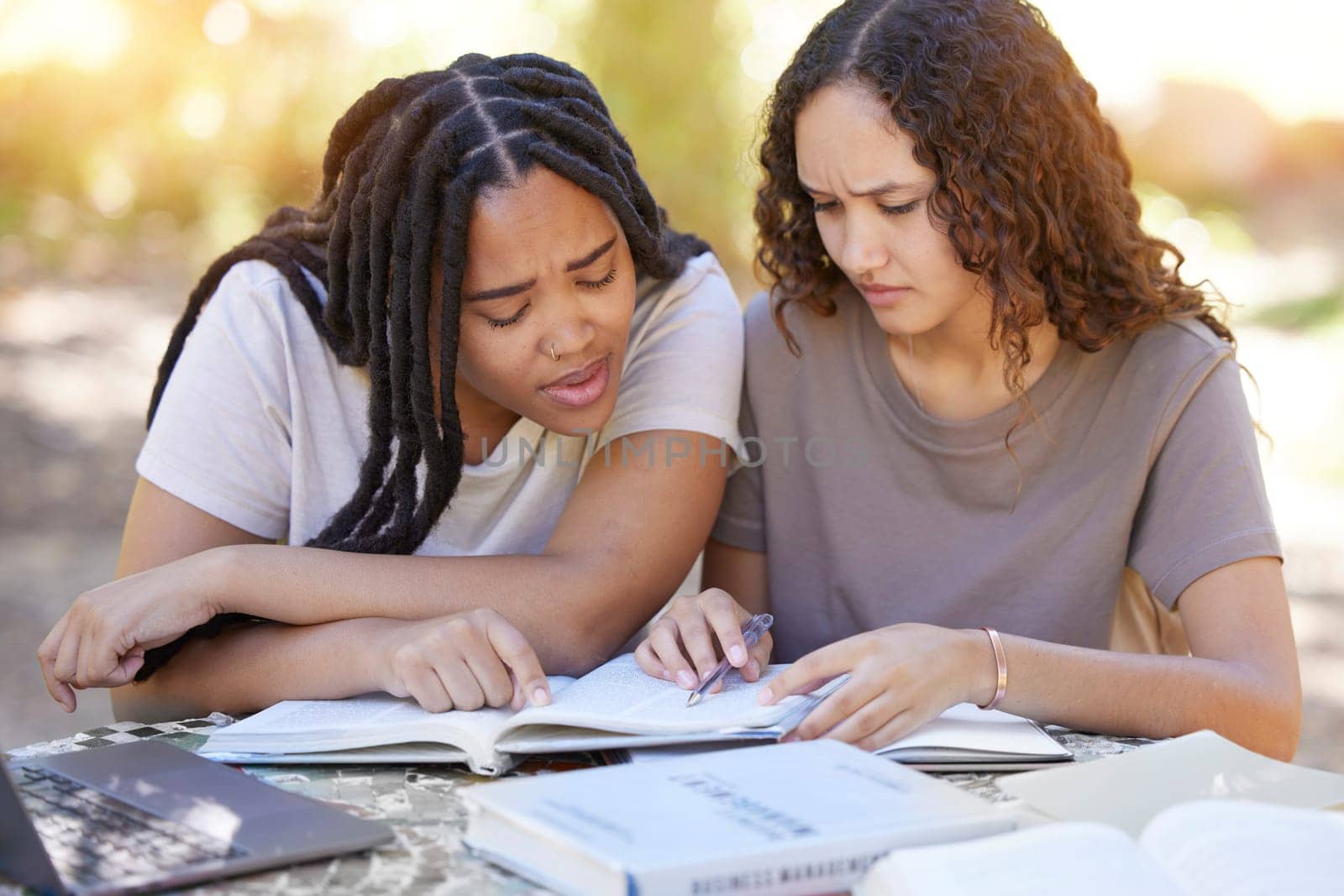 Students, confused and reading book, help and studying at park. University, education teamwork and doubt or uncertain women or friends learning, research or helping with textbook assignment outdoors by YuriArcurs