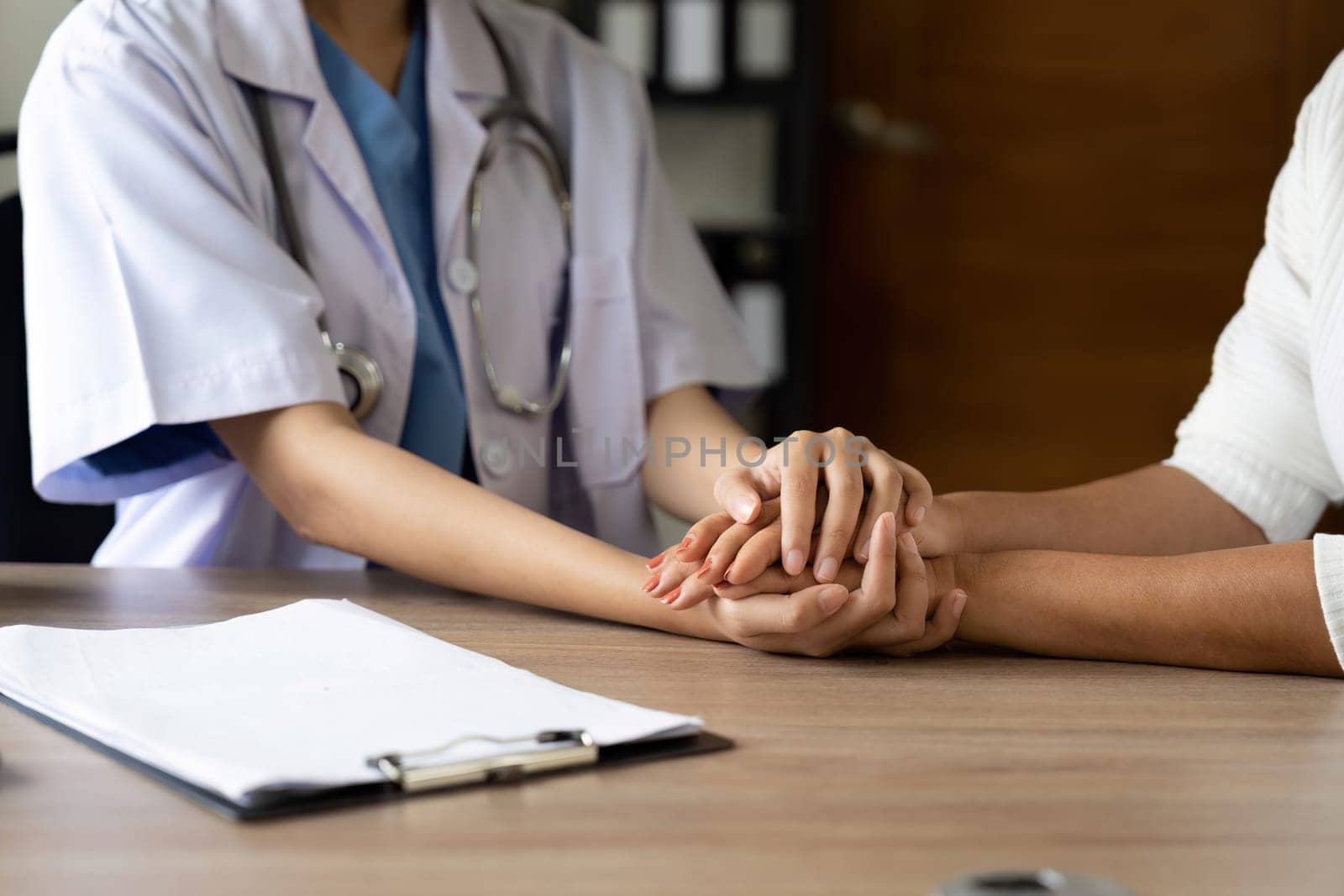 Hand of doctor reassuring her senior female patient. Medical ethics and trust concept.