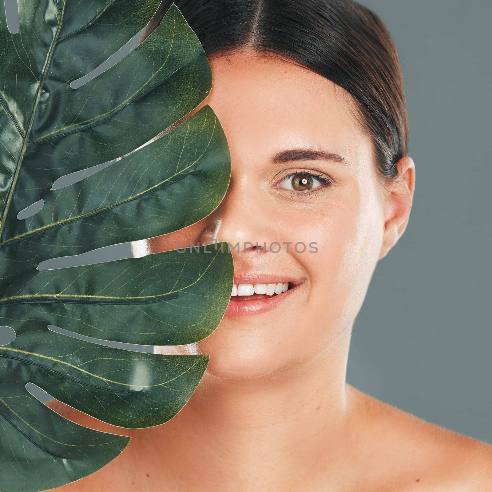 Palm leaf, face and woman in portrait with smile, beauty and skincare with natural cosmetics isolated in studio background. Healthy skin, wellness and glow, facial and eco friendly cosmetic treatment.