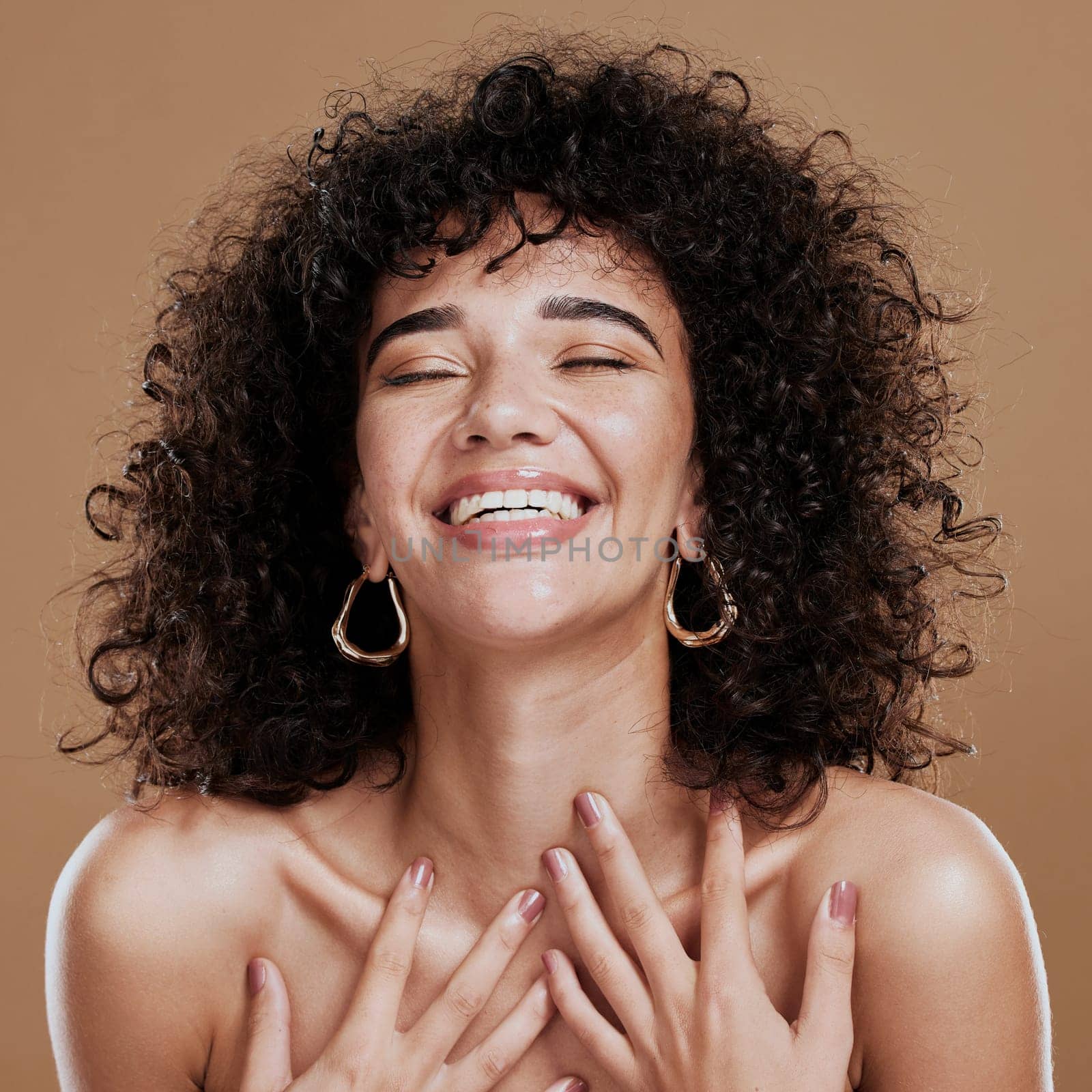 Beauty, skincare and self love of a black woman with natural hair feeling happiness and pride for identity on a brown studio background. Aesthetic model happt about cosmetics, makeup and glow on skin.