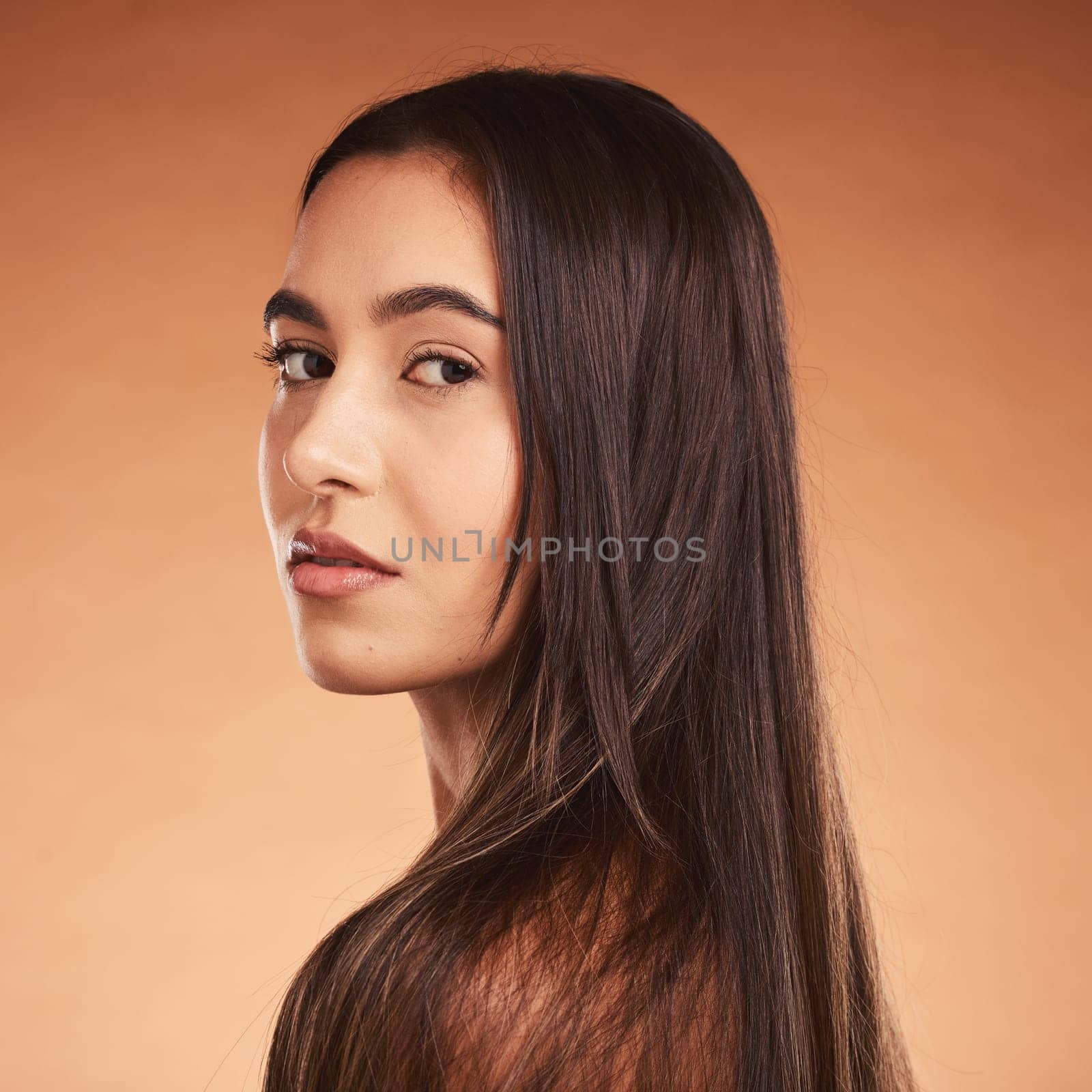 Hair care, beauty and face portrait of woman on brown studio background. Luxury makeup, skincare and female model with beautiful, healthy and long hair after salon hair treatment for clean hairstyle