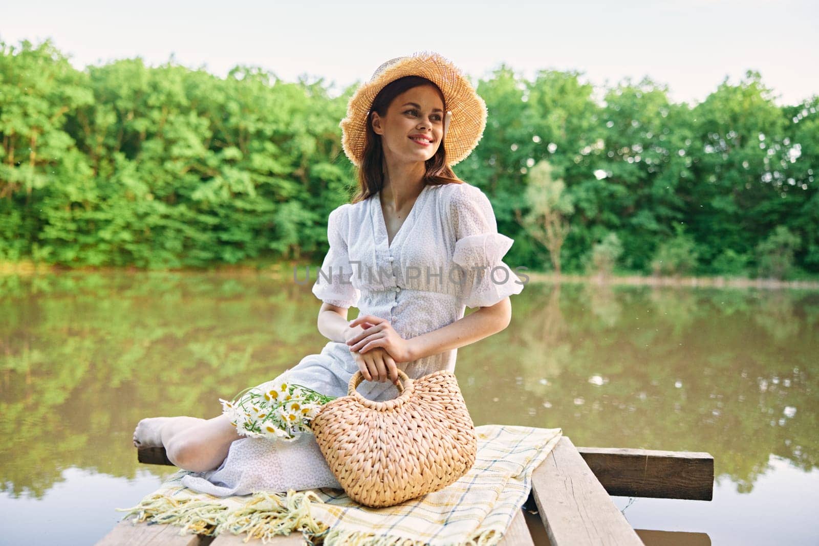 happy woman in a wicker hat resting in nature by the lake in summer. High quality photo