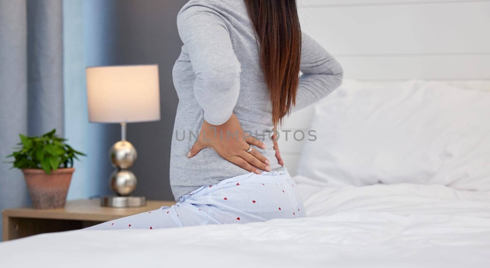 Tired, feeling and pregnant woman with back pain on a bed for rest, injury and fatigue. Healthcare, stress and girl with backache during pregnancy in her bedroom with morning sickness and cramps by YuriArcurs