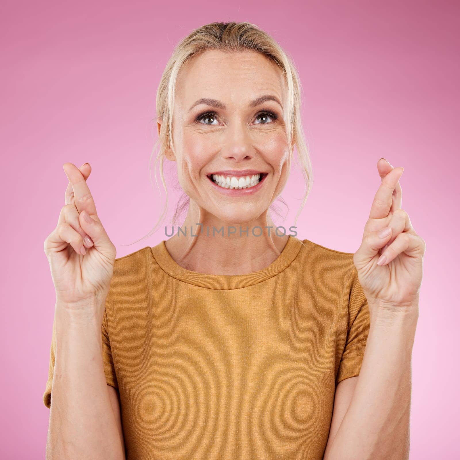Woman, fingers crossed and smile in studio, pink background and good luck face. Excited female model hope for bonus, promotion and winning giveaway with hand emoji sign, competition prize and lottery.