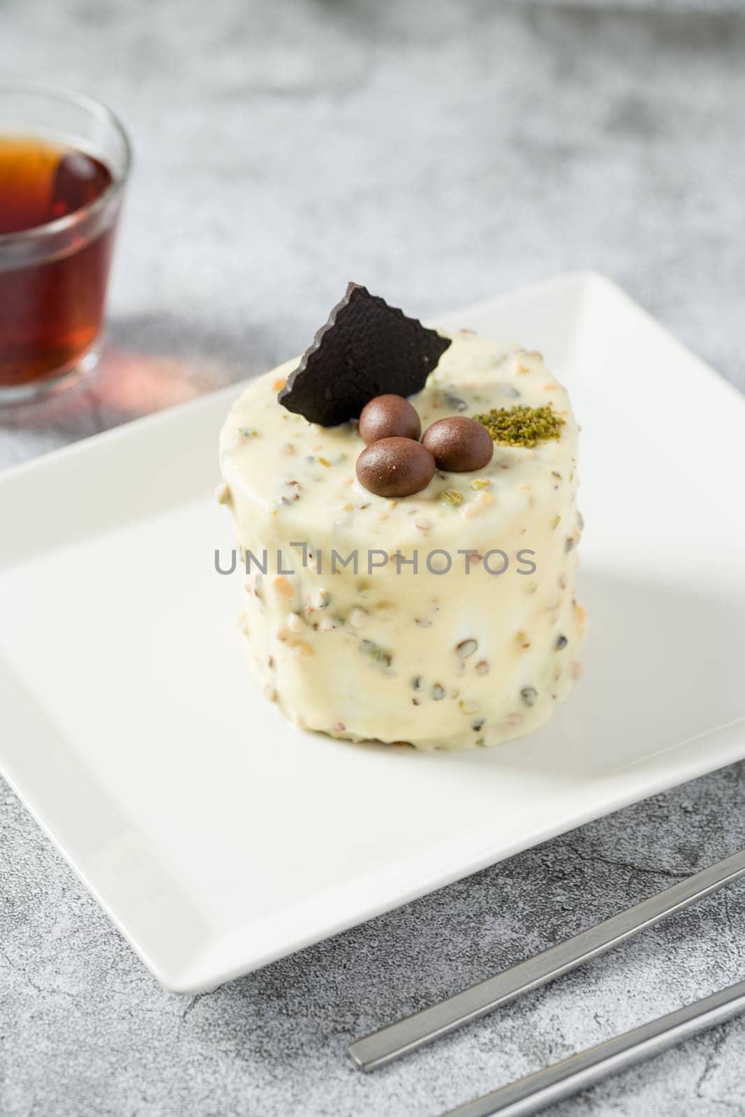 Single person mini cake with pistachio and white chocolate on a white porcelain plate by Sonat