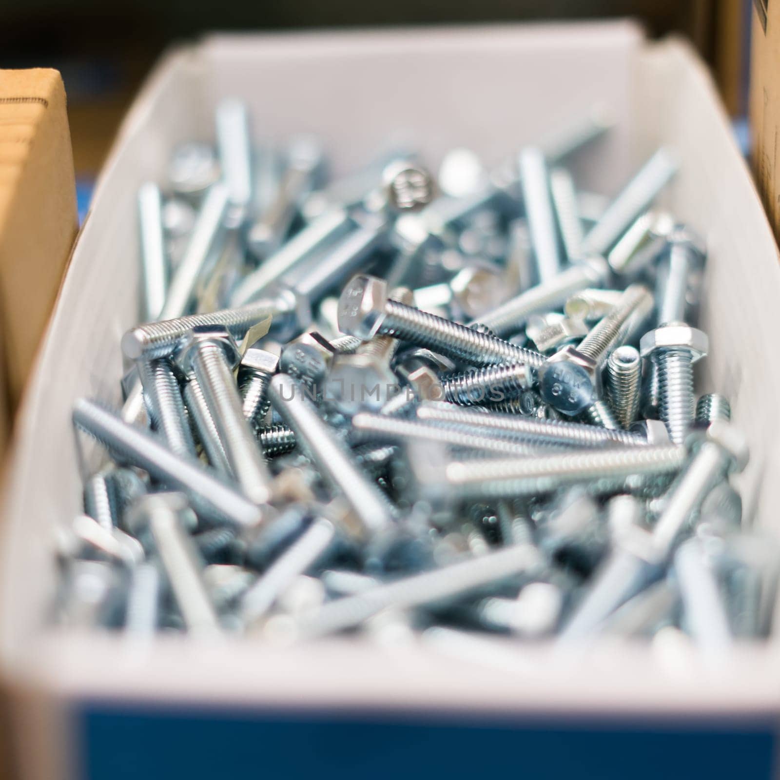 Small thin metal nails, hardware, screw lying in a store container. by Zelenin