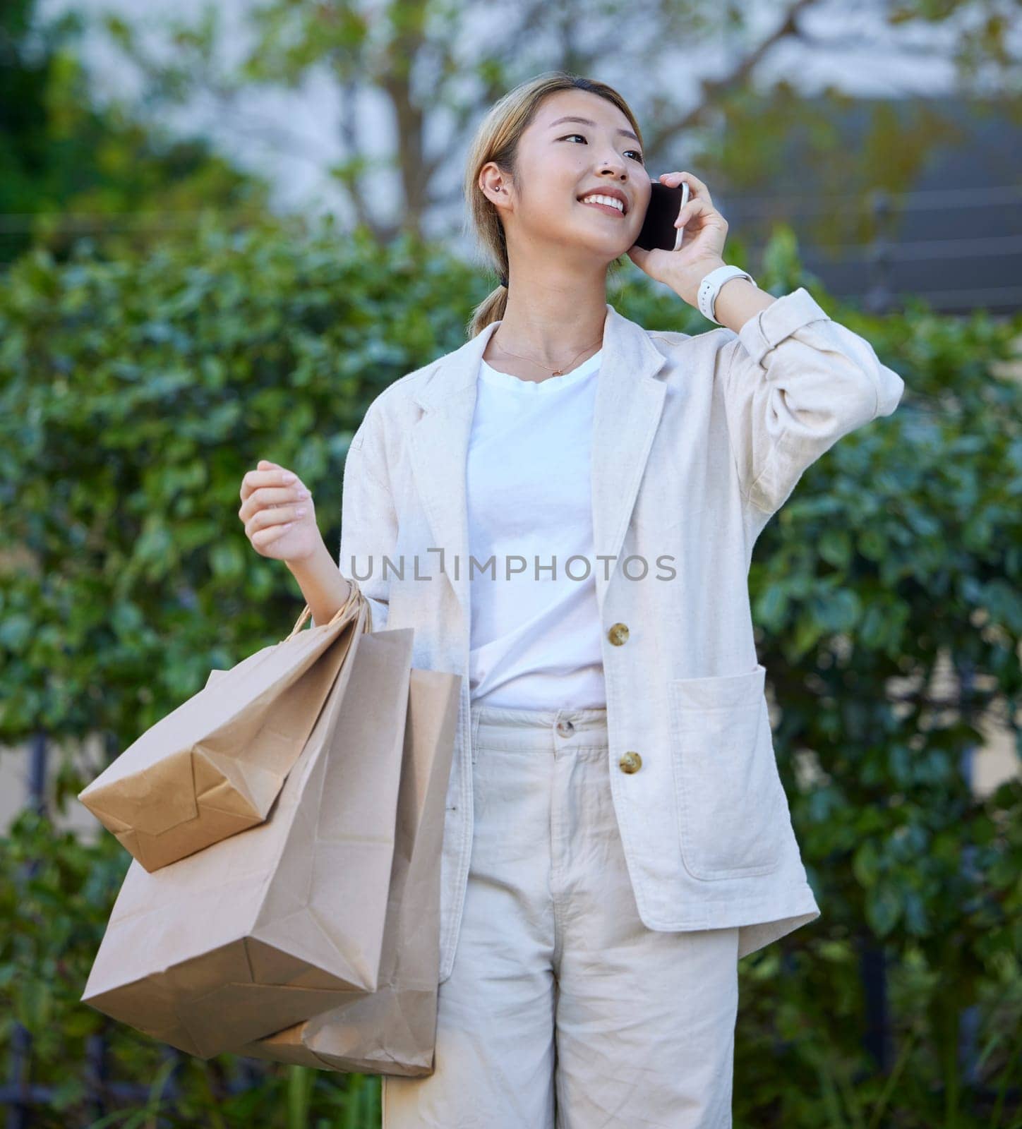 Phone call, Asian woman and shopping bags of a gen z person with mobile connection outdoor. Happy, communication and conversation after shop discount sale and promotion at a mall or luxury boutique.