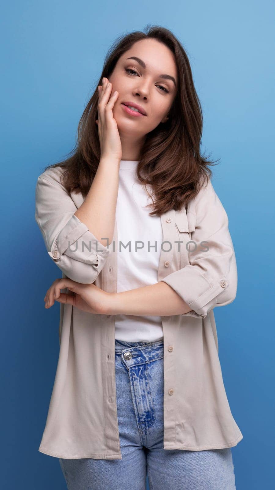 romantic charming brunette 30 year old female person dressed in a shirt and jeans on a studio background.
