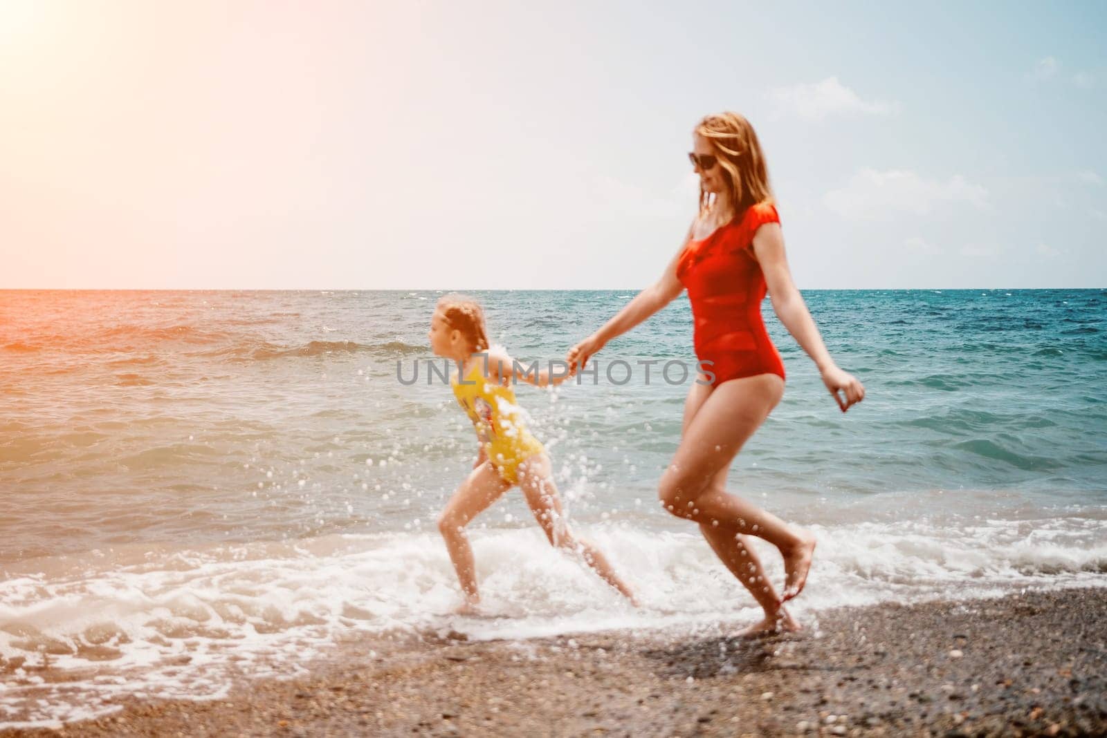 Happy loving family mother and daughter having fun together on the beach. Mum playing with her kid in holiday vacation next to the ocean - Family lifestyle and love concept.