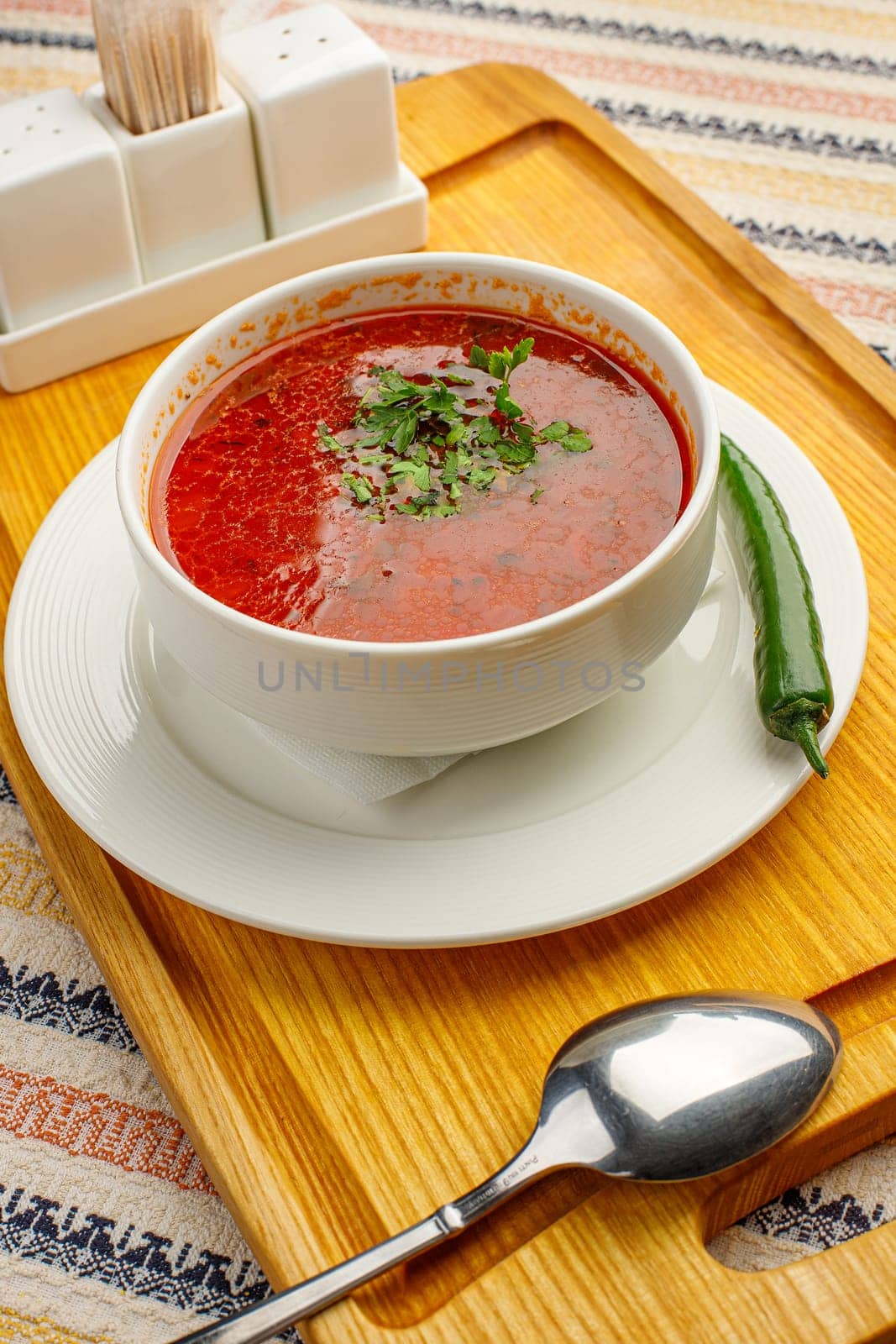 Beetroot soup borsch with garlic, chilly pepper and dill in a white bowl