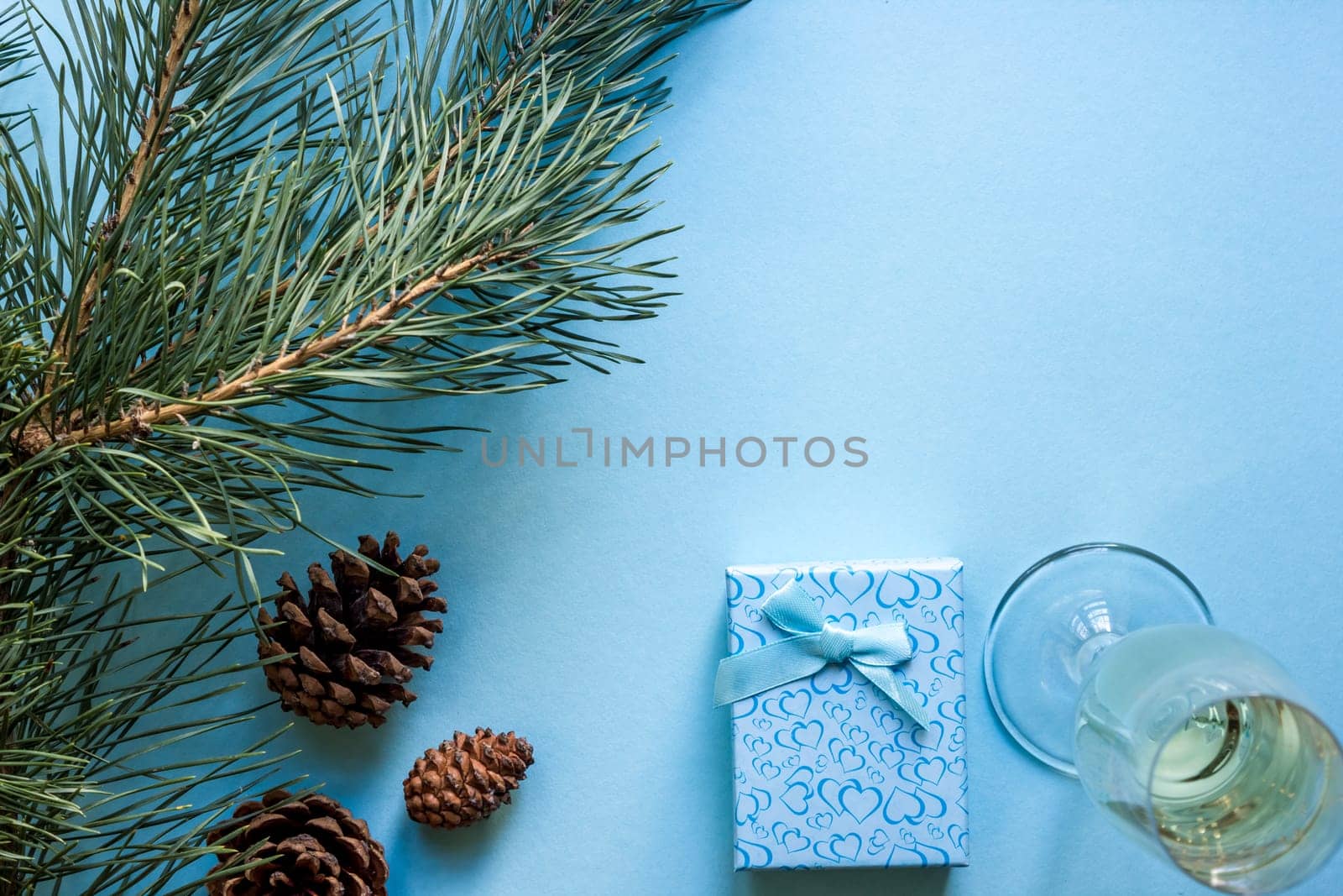 New Year's still life - a glass of champagne, Christmas decorations and spruce branches on blue background. Top view. Copy space. Flat lay