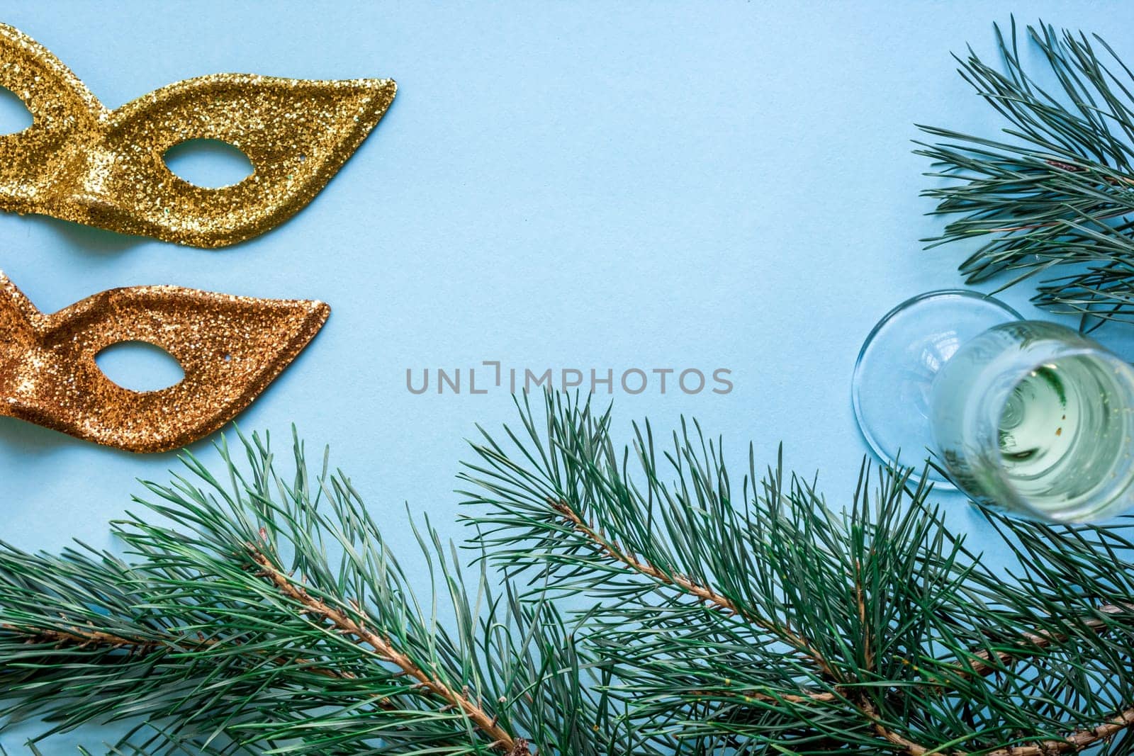 New Year's still life - a glass of champagne, Christmas decorations and spruce branches on blue background. Top view. Copy space. Flat lay