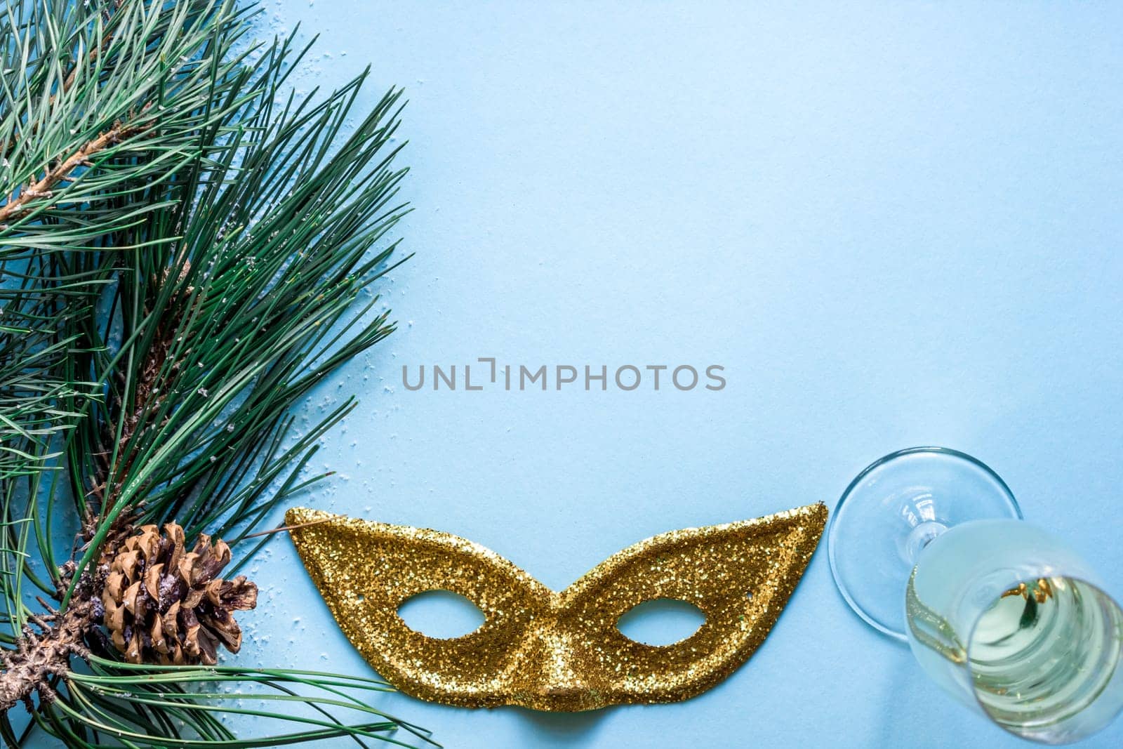 New Year's still life - a glass of champagne, Christmas decorations and spruce branches on blue background. Top view. Copy space. Flat lay