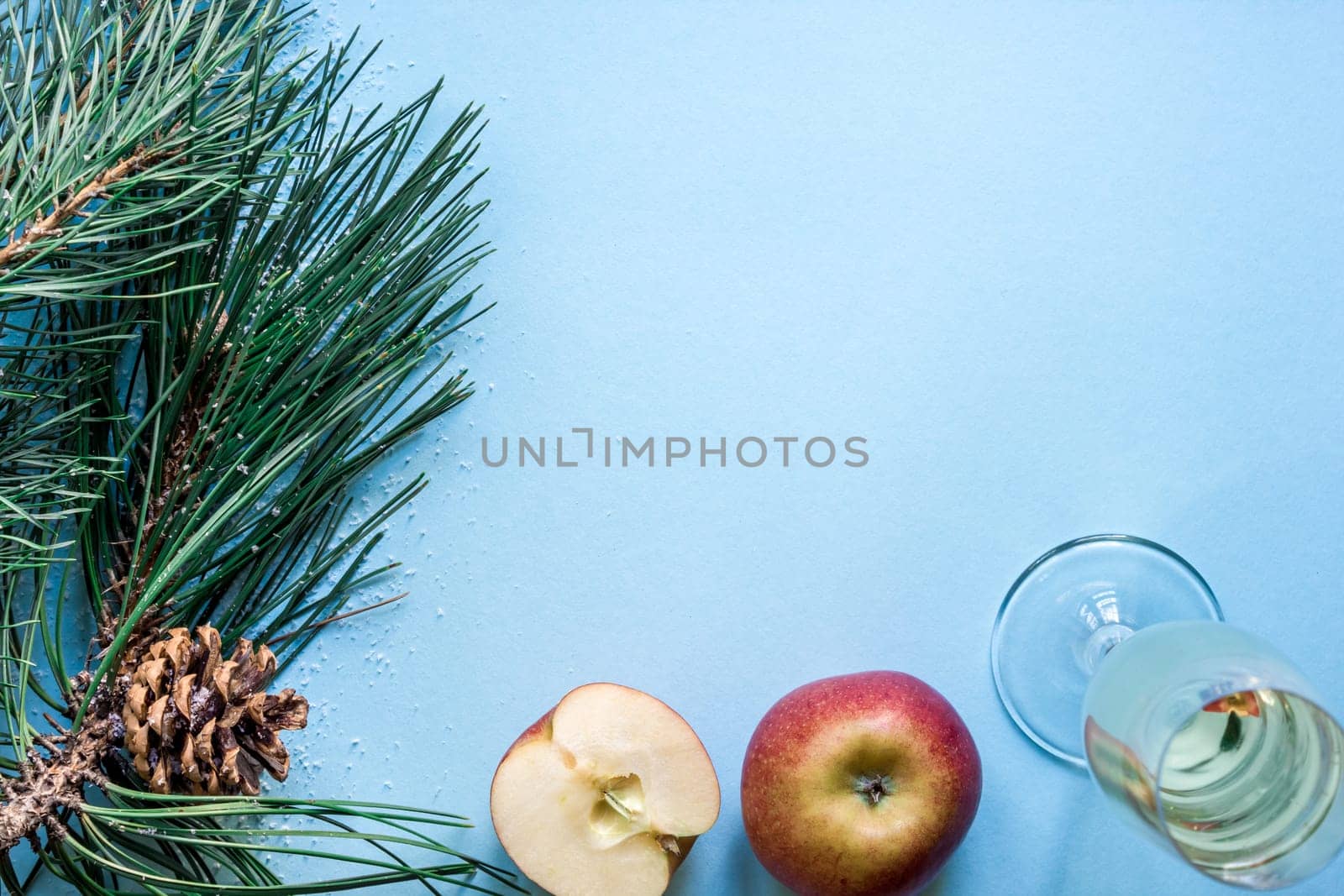 New Year's still life - a glass of champagne, Christmas decorations and spruce branches on blue background. Top view. Copy space. Flat lay
