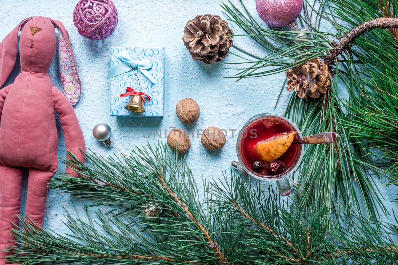 Hot mulled wine with orange, anise, cardamon and cinnamon on blue background. Christmas tree branches, gifts and cones. Flat lay, copy space, top view. Holidays.