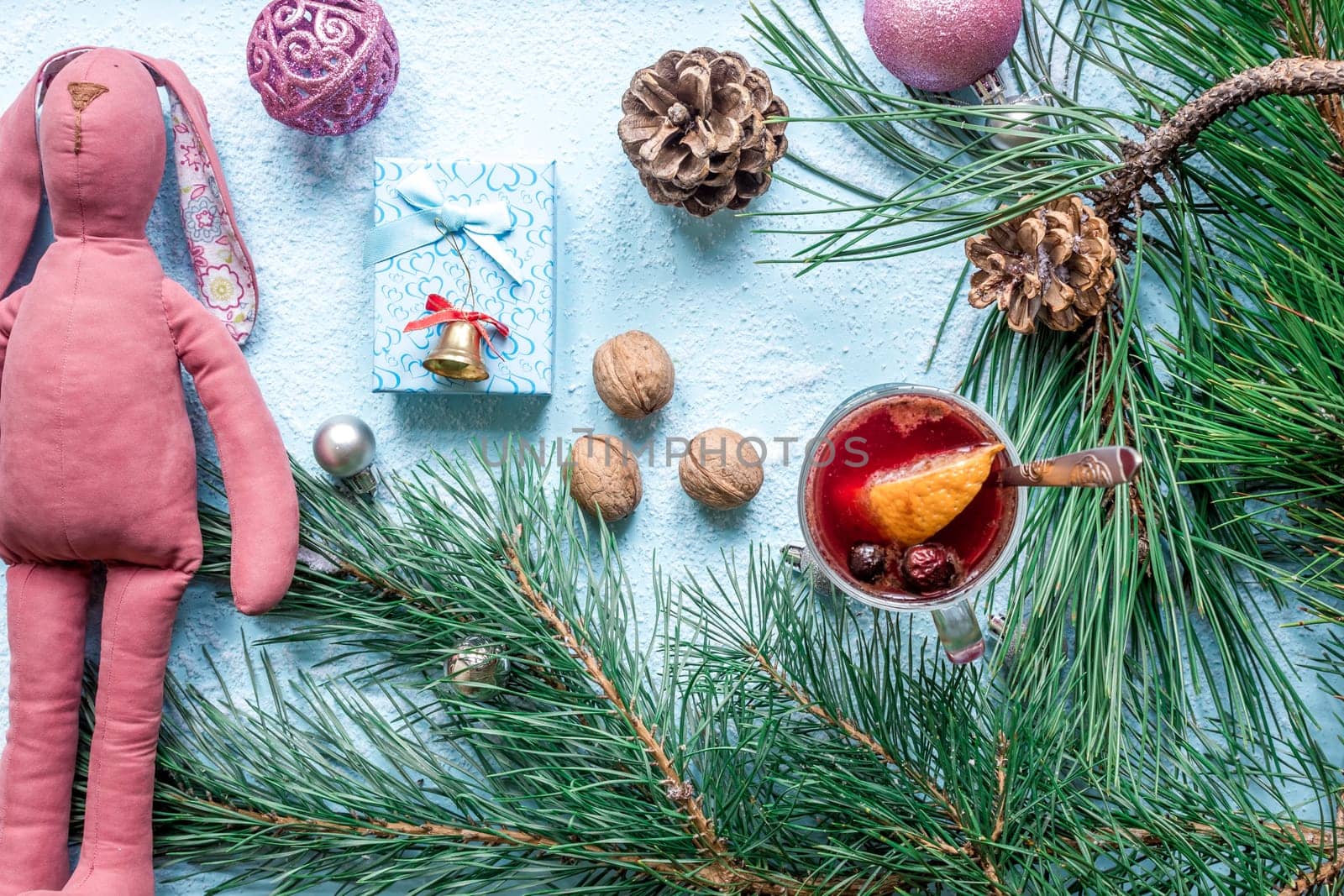 Hot mulled wine with orange, anise, cardamon and cinnamon on blue background. Christmas tree branches, gifts and cones. Flat lay, copy space, top view. Holidays.