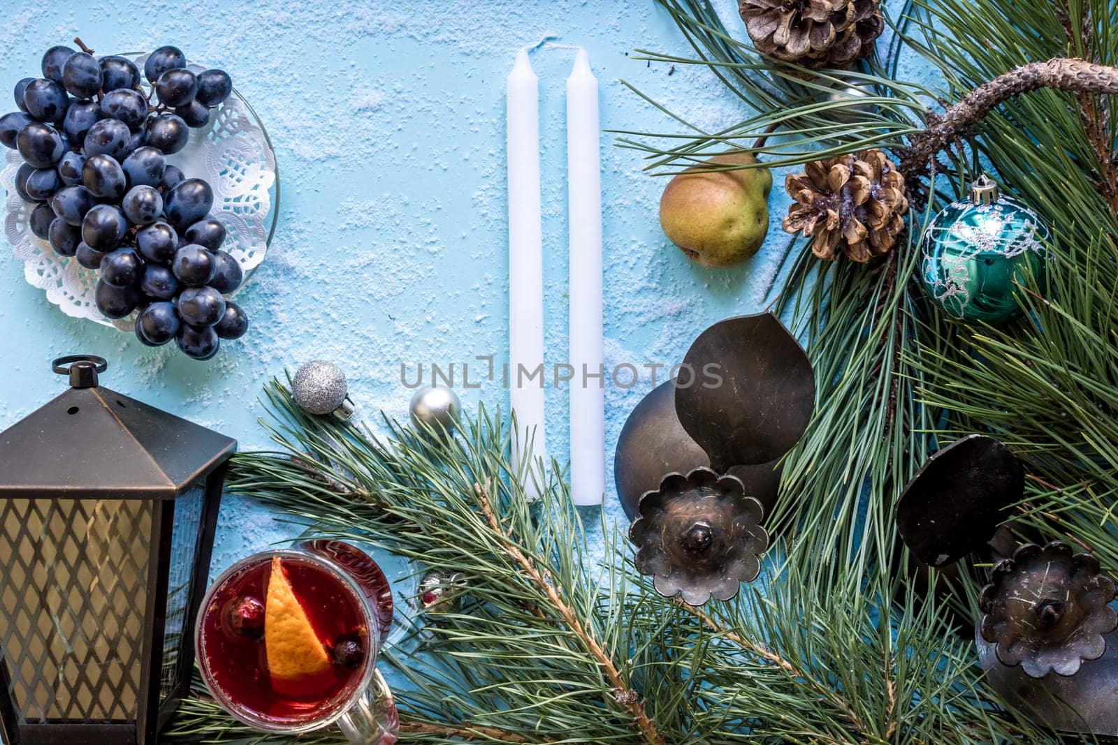 Hot mulled wine with orange, anise, cardamon and cinnamon on blue background. Christmas tree branches, gifts and cones. Flat lay, copy space, top view. Holidays.