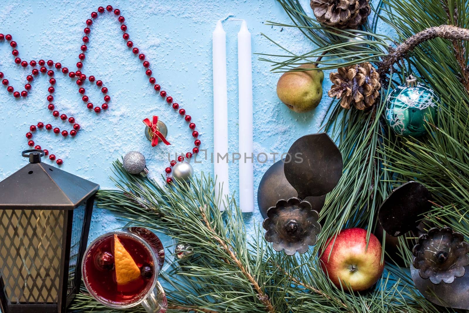Hot mulled wine with orange, anise, cardamon and cinnamon on blue background. Christmas tree branches, gifts and cones. Flat lay, copy space, top view. Holidays.
