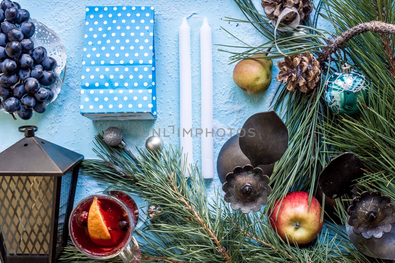 Hot mulled wine with orange, anise, cardamon and cinnamon on blue background. Christmas tree branches, gifts and cones. Flat lay, copy space, top view. Holidays.