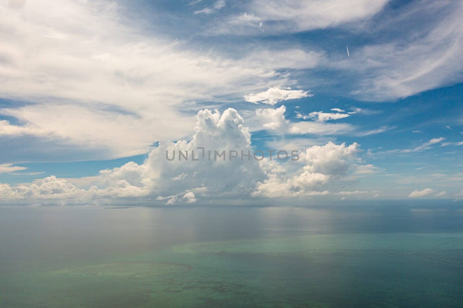 Beautiful white clouds on blue sky over calm sea. Tranquil sea harmony of calm water surface. Sunny sky and calm blue ocean.