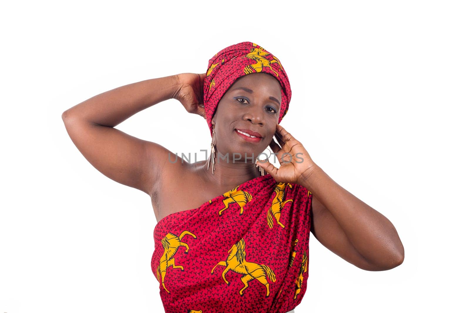 young african woman standing in loincloth in a studio hand on the neck looking at camera smiling.