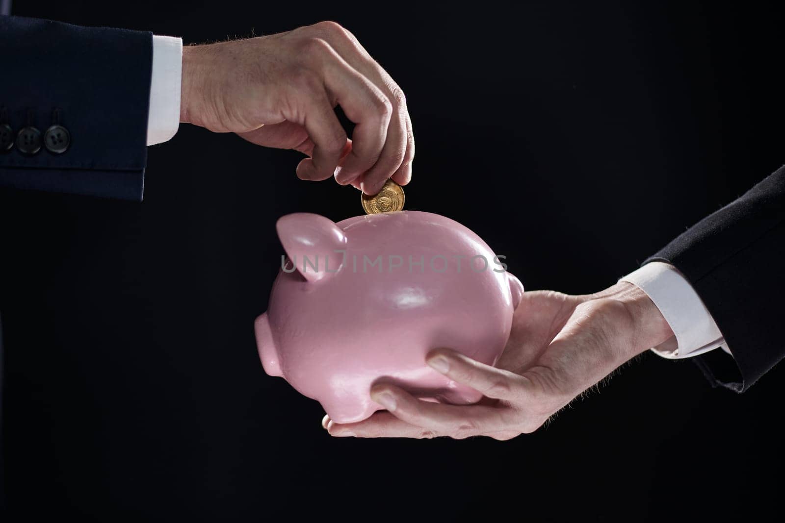 Hand puts a coin in a piggy bank on a black background. accumulation concept