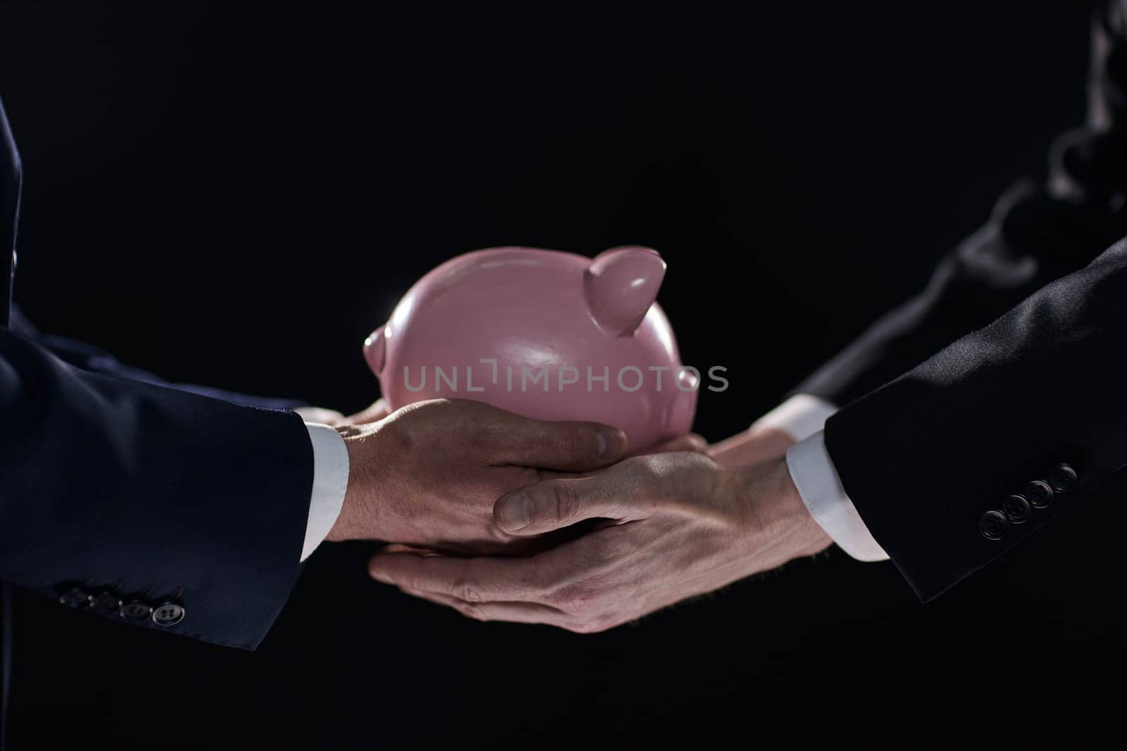 A businessman gives you a piggy bank isolated on a black background. banking