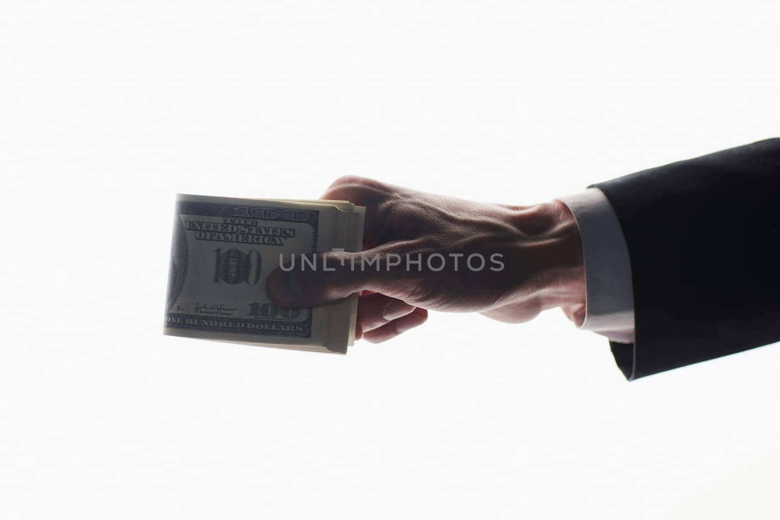 Close up of a man's hand crushing a wad of hundred dollar notes