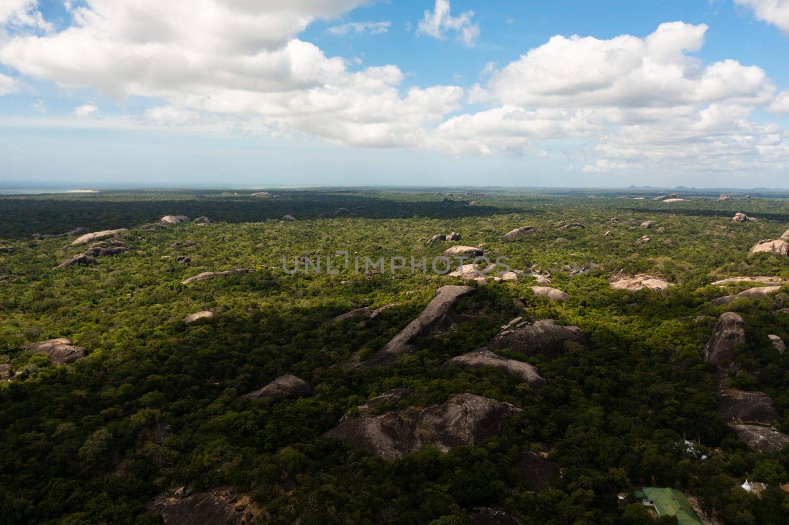 Aerial drone of Rocks among the rainforest and jungle against the blue sky and clouds. Sri Lanka, Okanda.