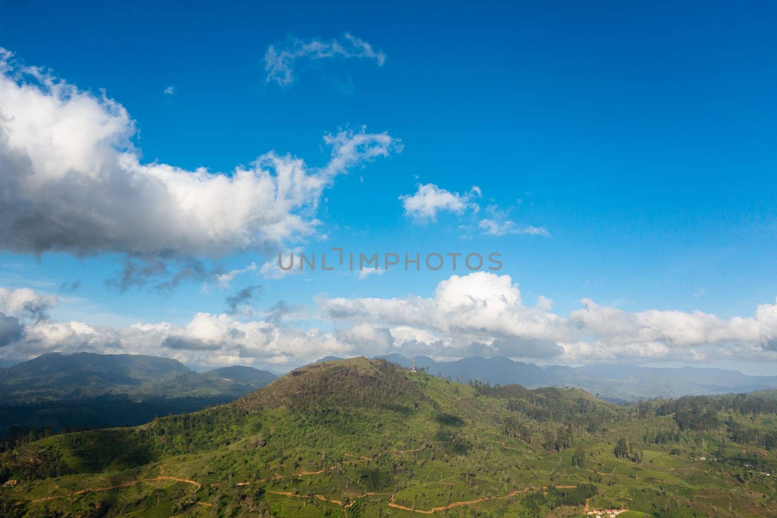 Aerial view of Green tea plantation against the blue sky and clouds in the mountains. Tea estate landscape. Maskeliya, Sri Lanka.