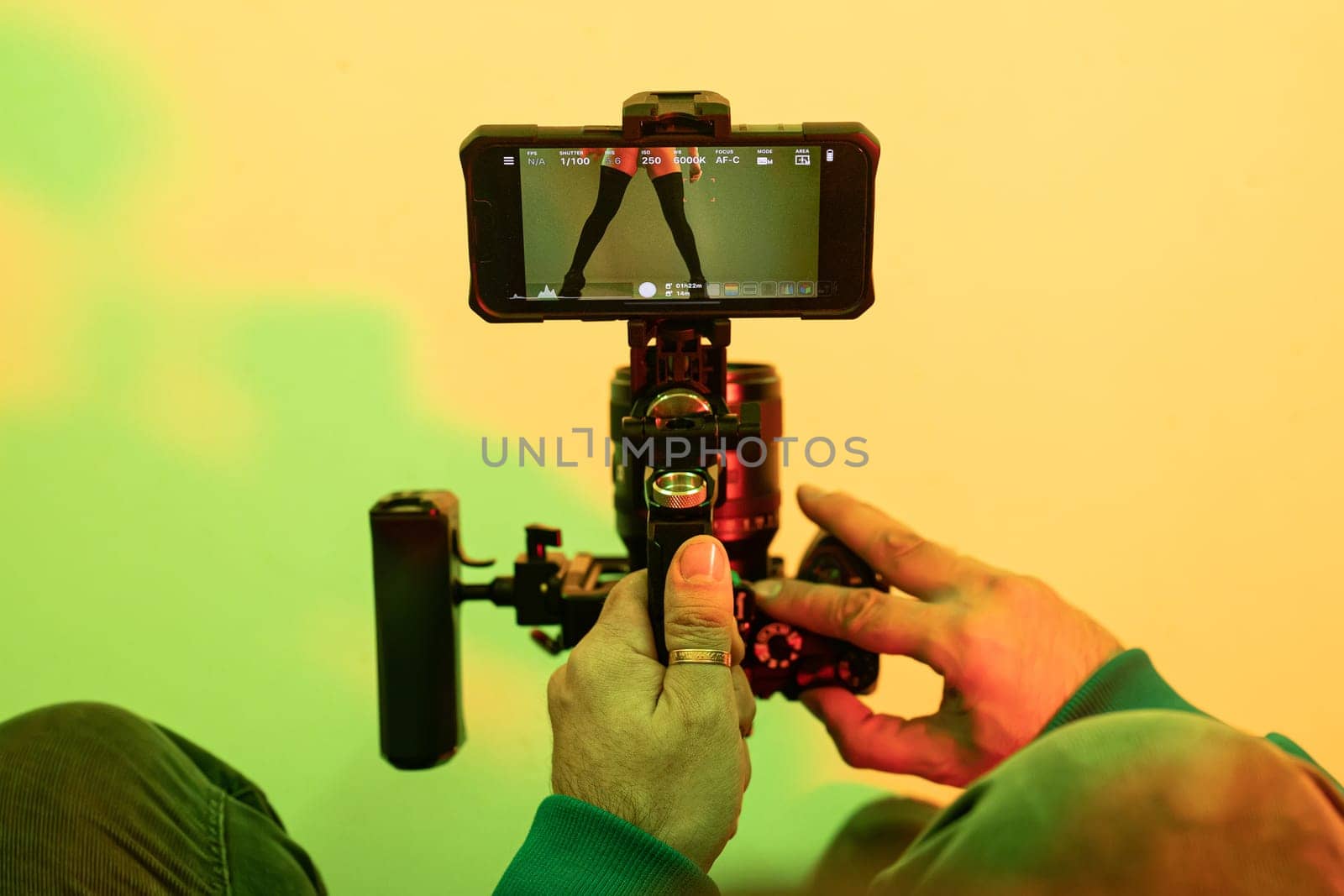 Backstage operator working with professional camera. Videographer shoots music clip with dancer or singer celebrity woman in studio with neon color light tubes. High quality photo