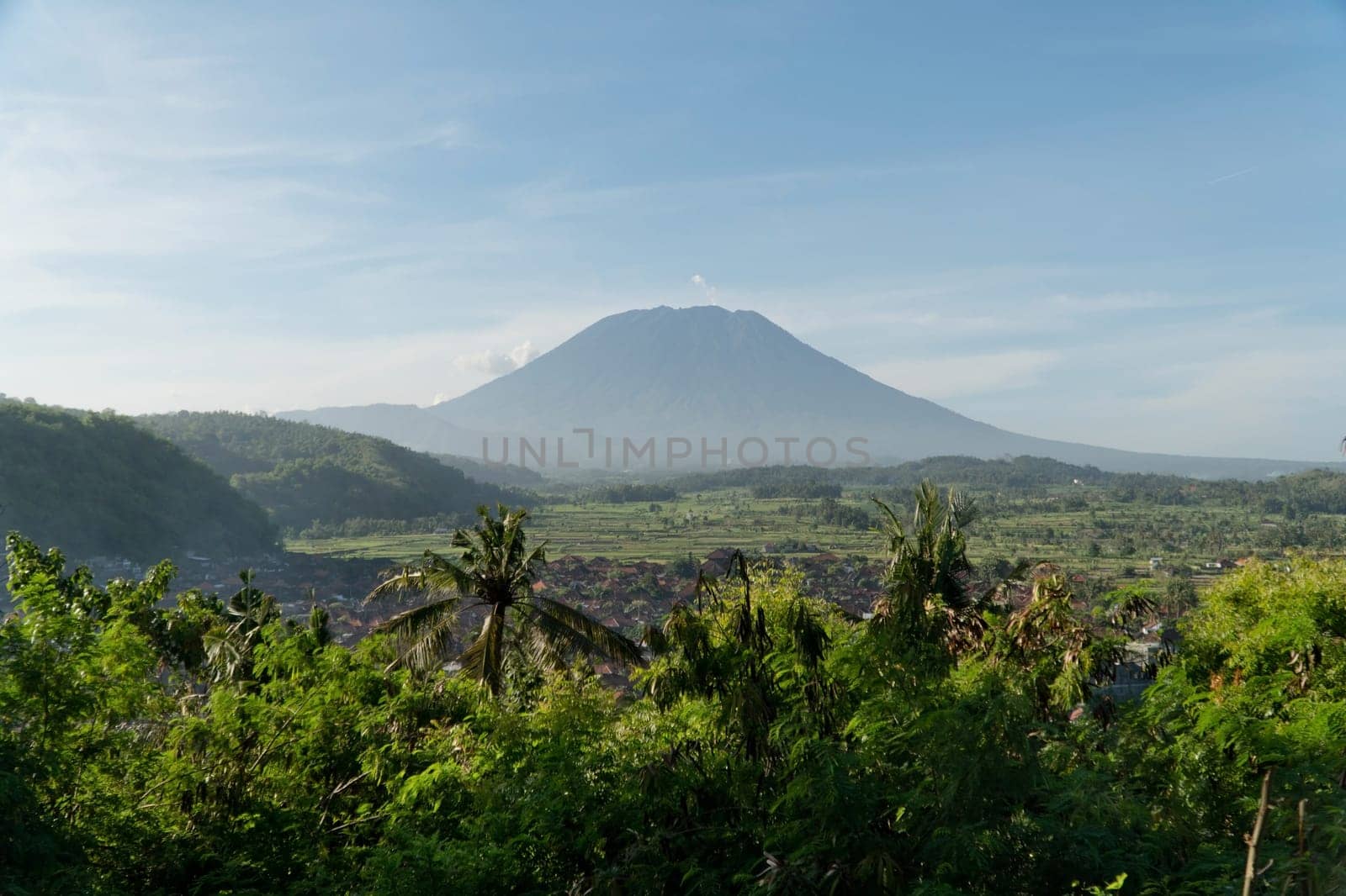 Aerial view Town near volcano Agung, rice terrace, farmlands, village, fields with crops, agricultural land of farmers. Bali, Indonesia