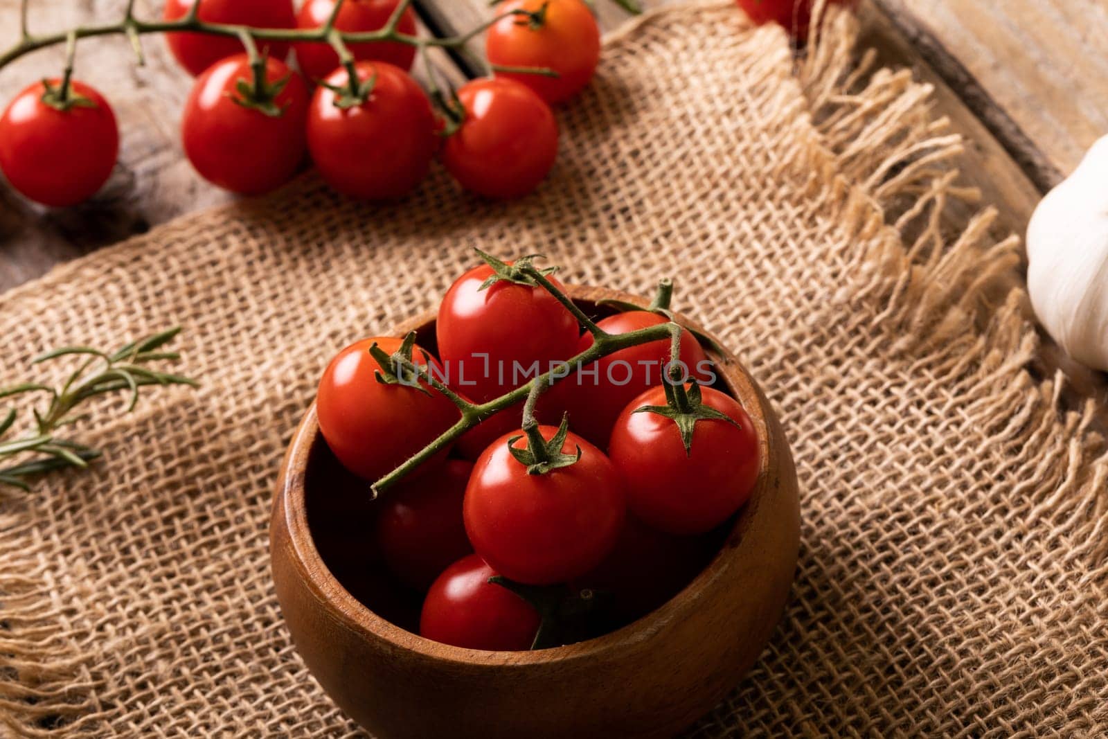 High angle view of fresh red cherry tomatoes in wooden bowl over burlap by Wavebreakmedia