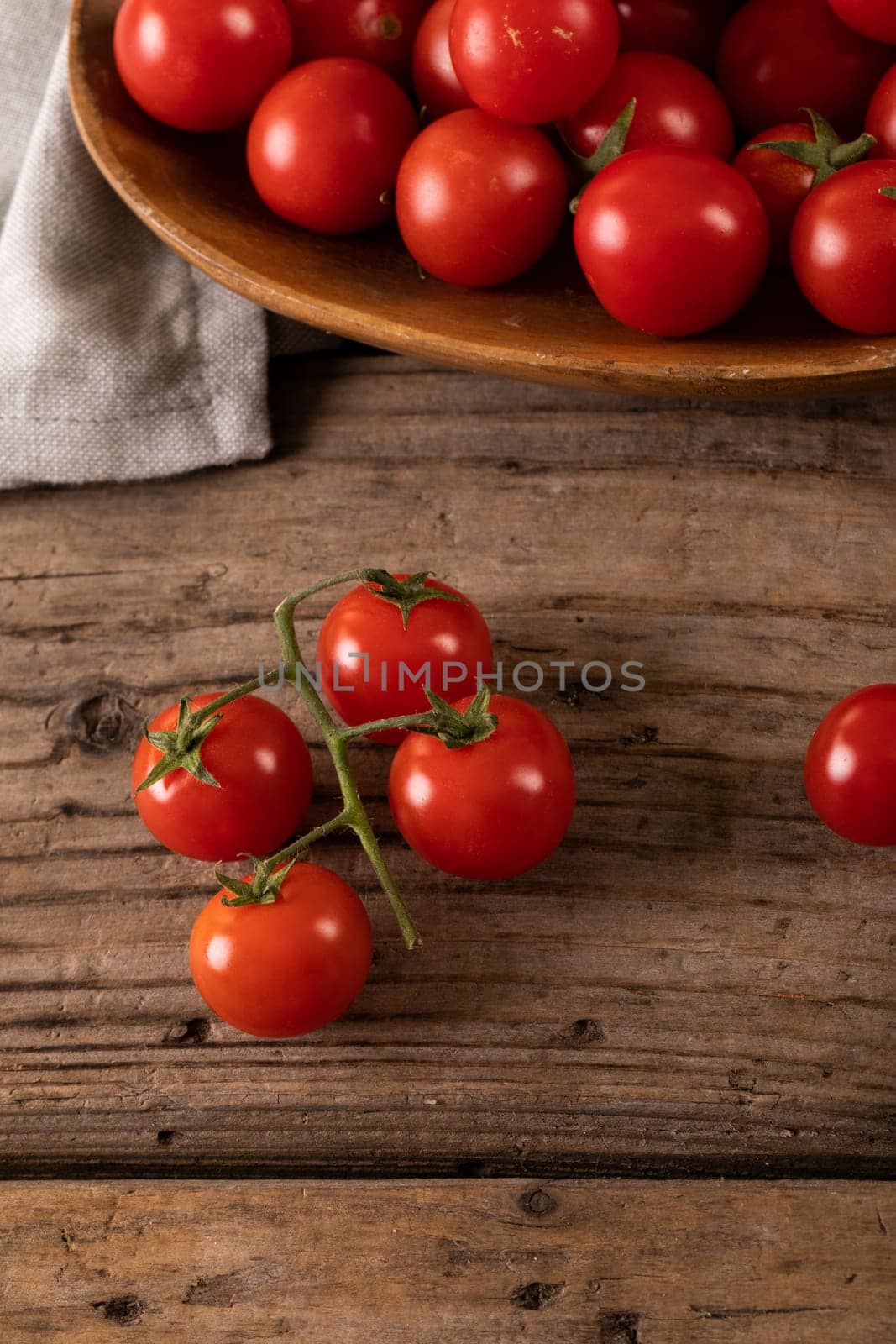 Directly above view of fresh red cherry tomatoes with plate and napkin on wooden table by Wavebreakmedia