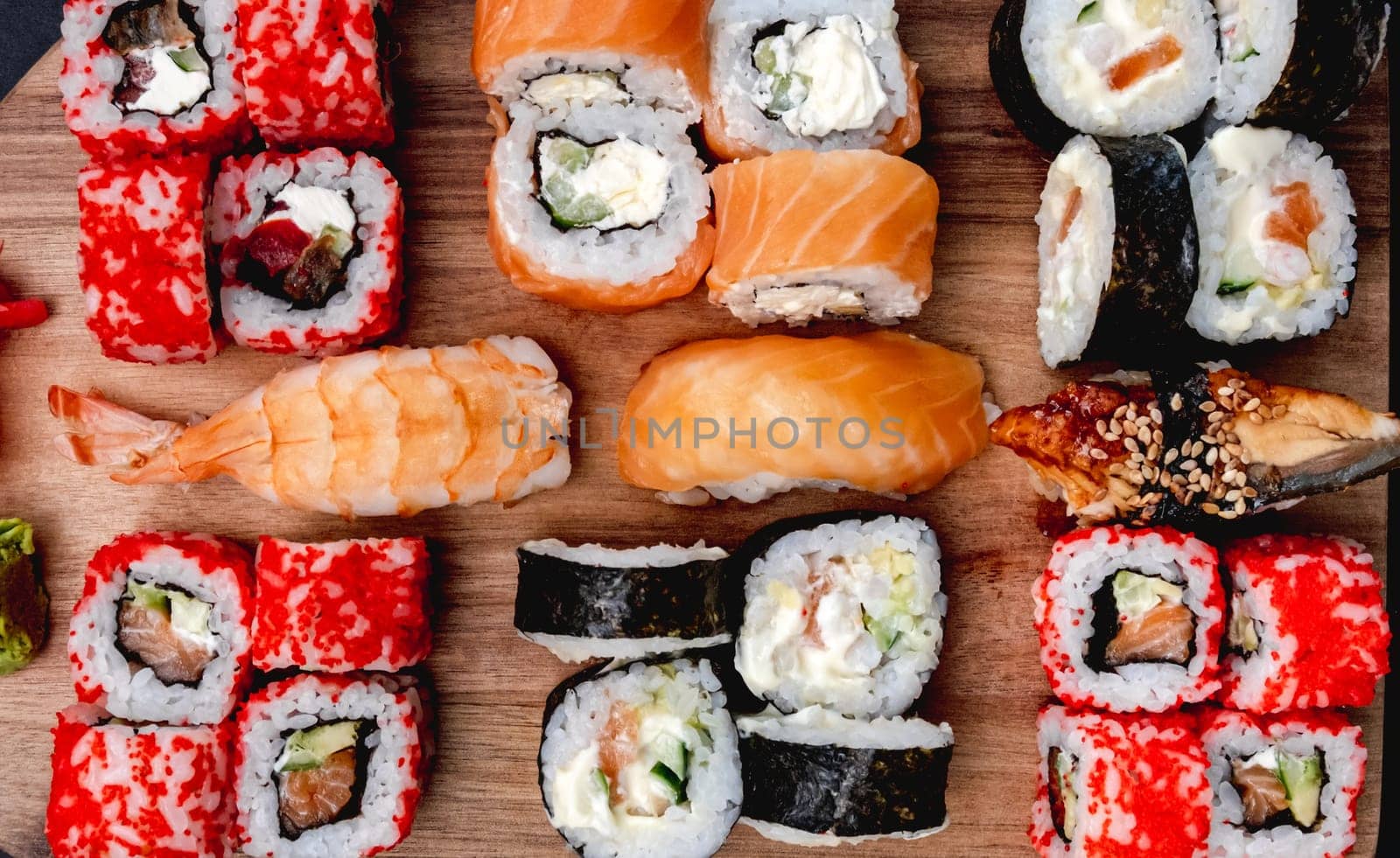 Colorful sushi maki set on wooden desk with shrimps, rice and salmon. Oriental japanese healthy cuisine with raw seafood