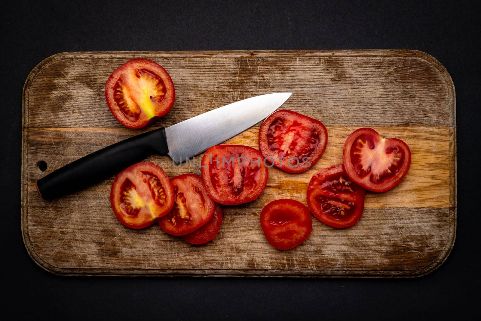 Sliced cherry tomatoes with knife on wooden board on background with copyspace. Healthy organic pomodoro vegetable for bruschetta view from above