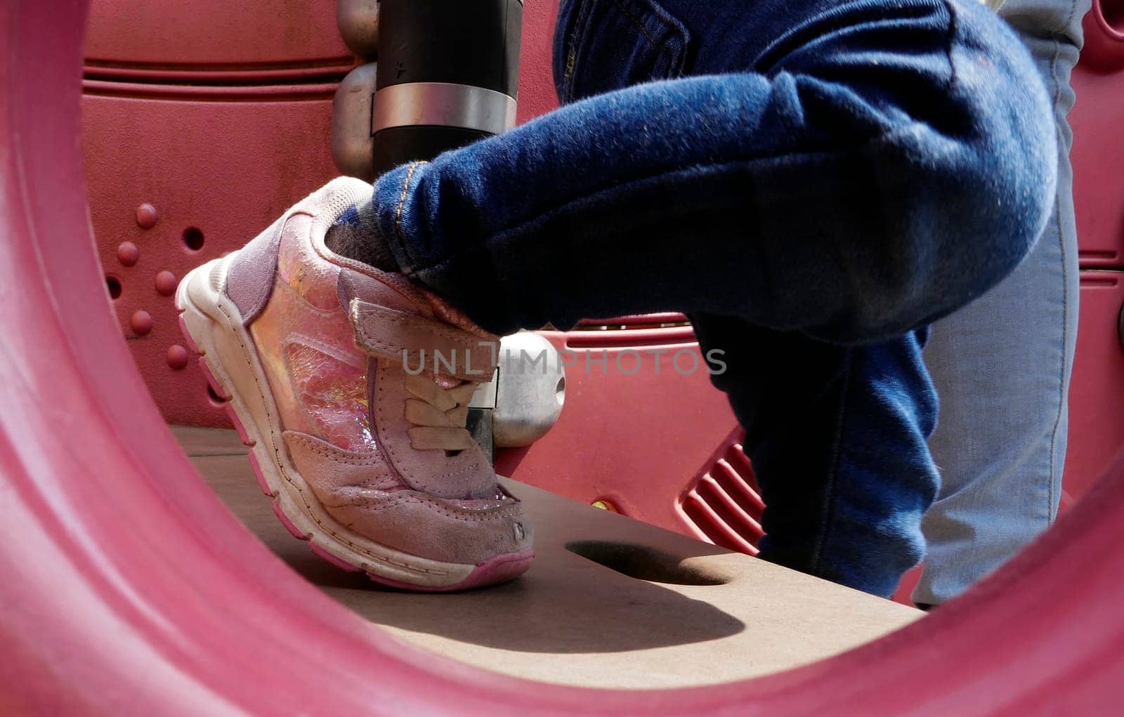 Feet of a two year old girl stepping down. She proudly wears trendy pink sneakers