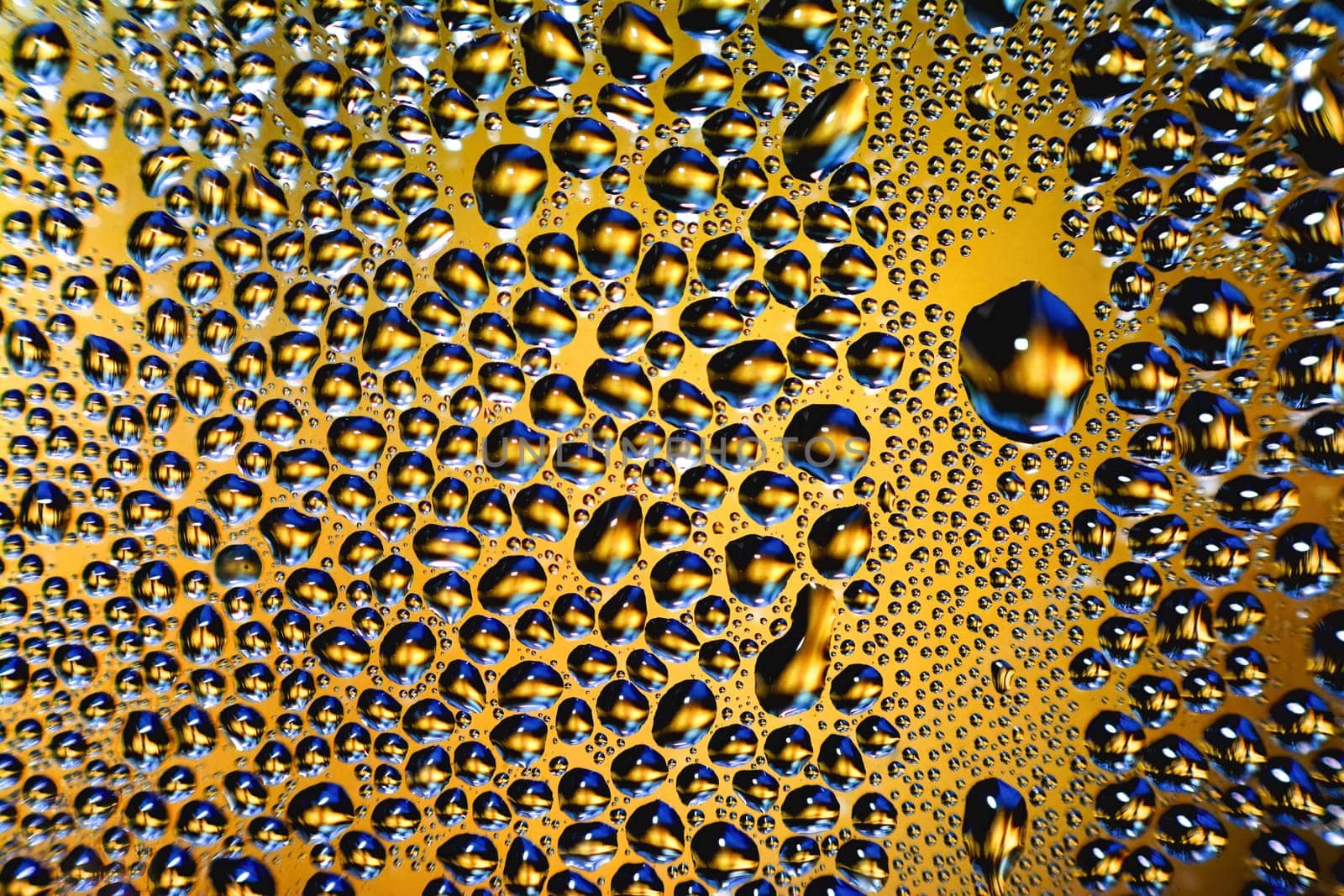 glass covered with drops of water. water drops on yellow background texture.