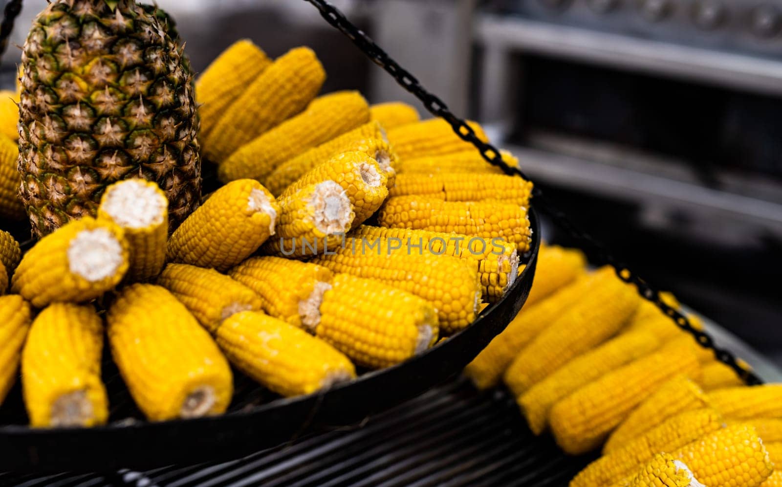 Boiled corn and pineapple at street food market closeup. Fresh yellow vegetables maize and fruits at traditional fair festival