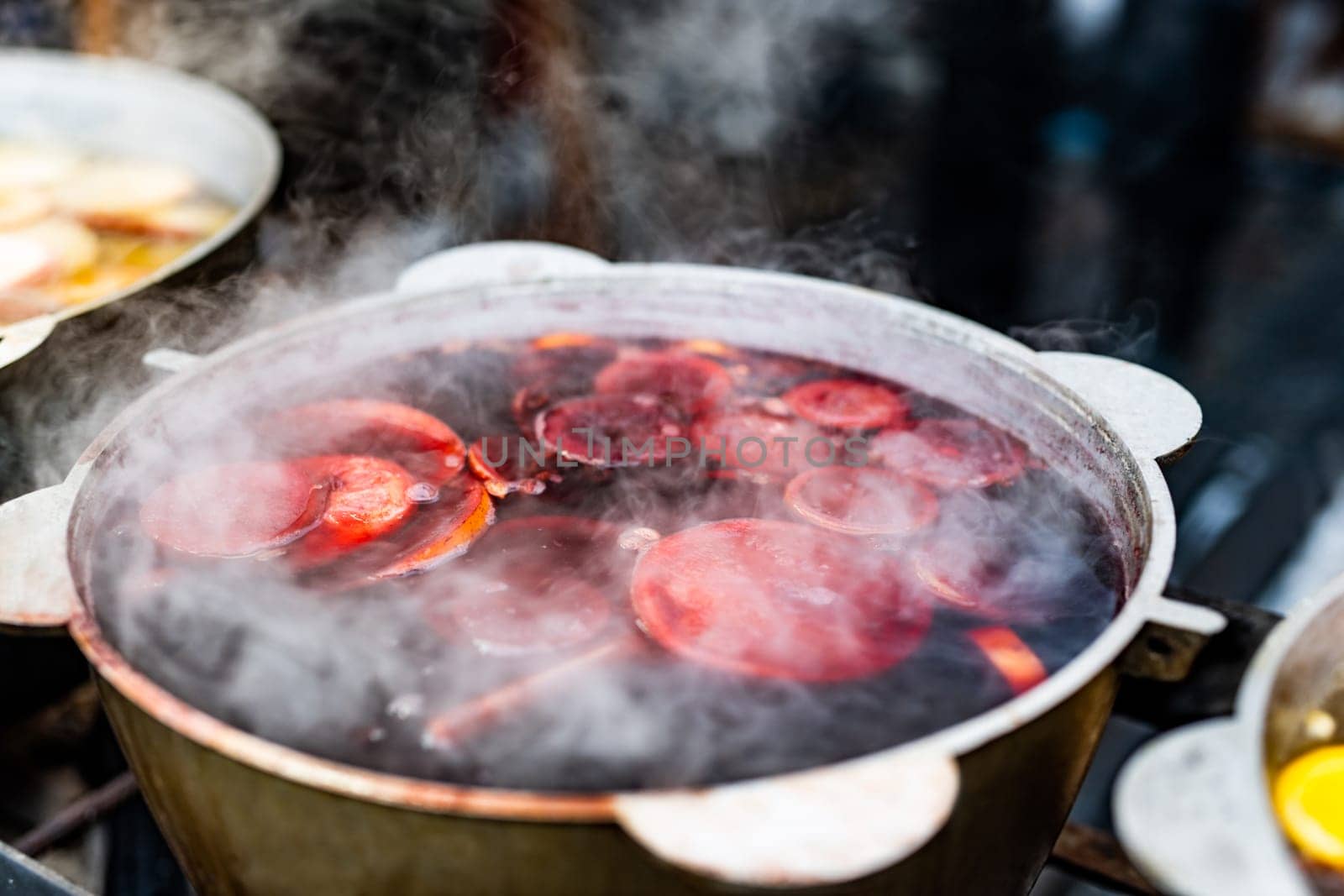 Beverages berries hot mulled wine in pots in street food market at Christmas time. Colorful festive hot drinks at fair xmas festival outdoors closeup