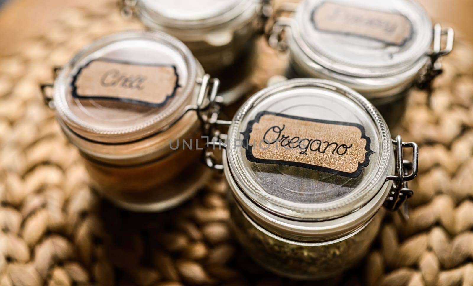 Set of different spicies in glass jars at the kitchen. Black pepper and dried greens.