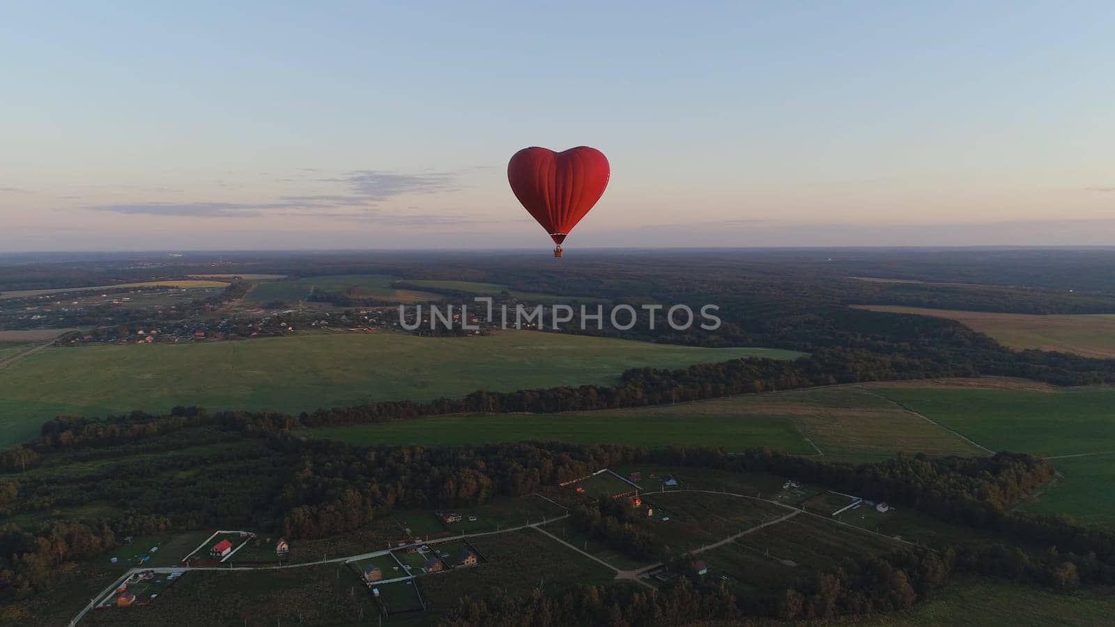 Aerial view Hot air balloon shape heart in sky over field in countryside, beautiful sky and sunset. Aerostat fly over countryside.