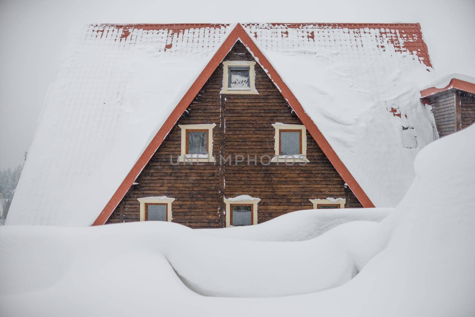 The roof of a wooden house. Large snow drifts. Triangular roof with windows. by Renisons
