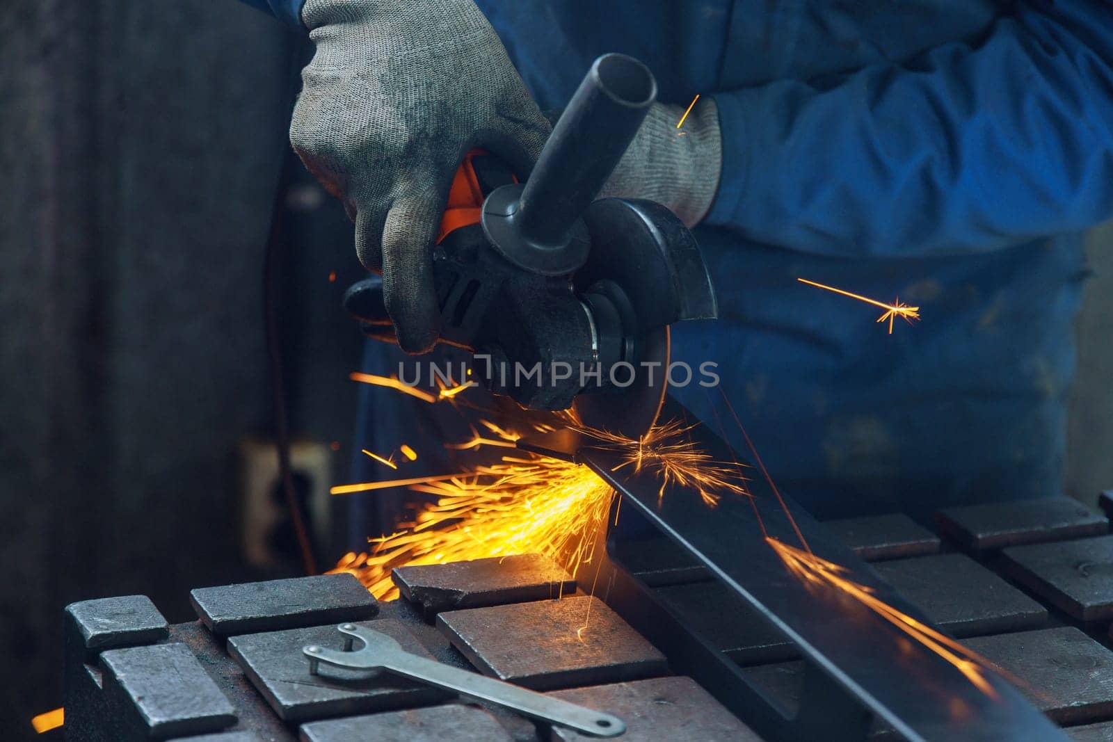 Metalwork workplace has master grinding metal an electric spark is generated as he grinds metal in factory