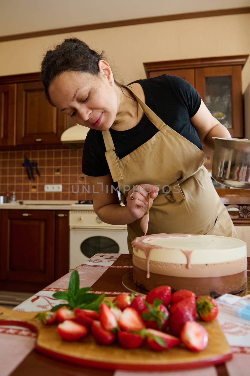 Inspired pregnant woman, pastry chef pouring ruby pink chocolate glaze on top of a triple chocolate mousse cake by artgf