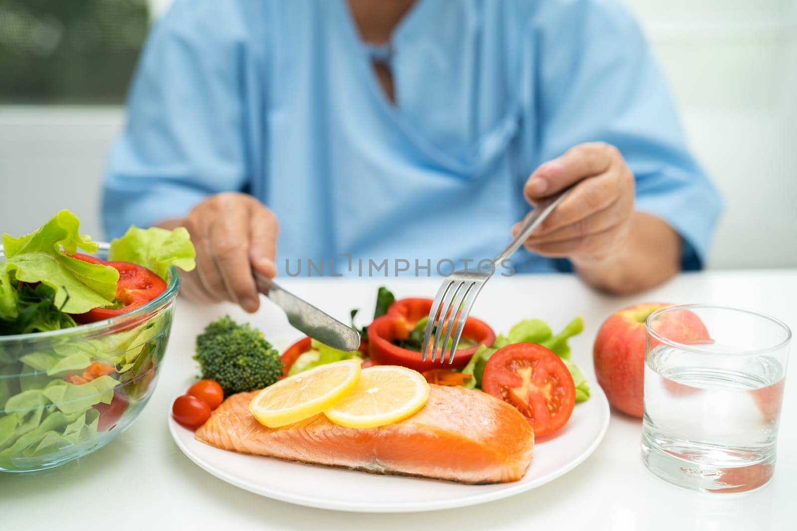 Asian elderly woman patient eating salmon steak breakfast with vegetable healthy food in hospital.