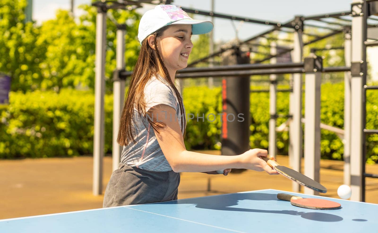 Little girl playing ping pong in park.