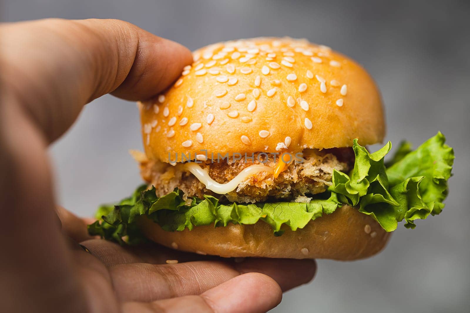 Hand holding a delicious hamburger with dark background for bakery, food and eating concept