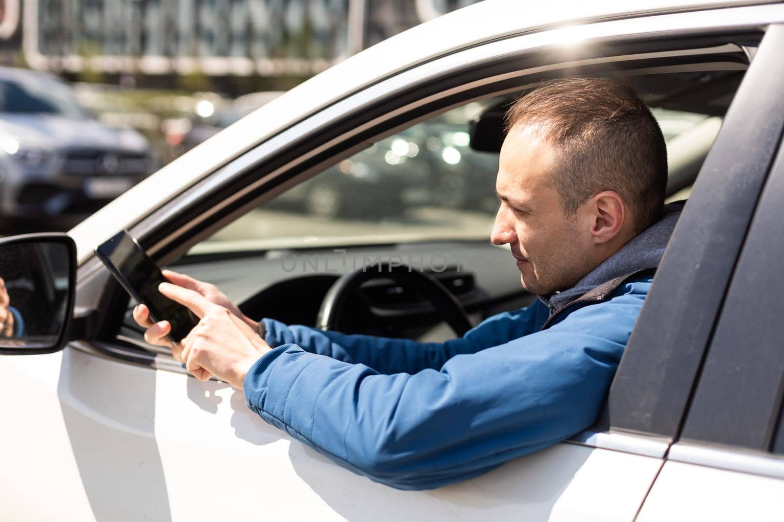 Smartphone man in car driving showing smart phone display smiling happy. Male driver using app showing blank empty screen sitting in drivers seat by Andelov13