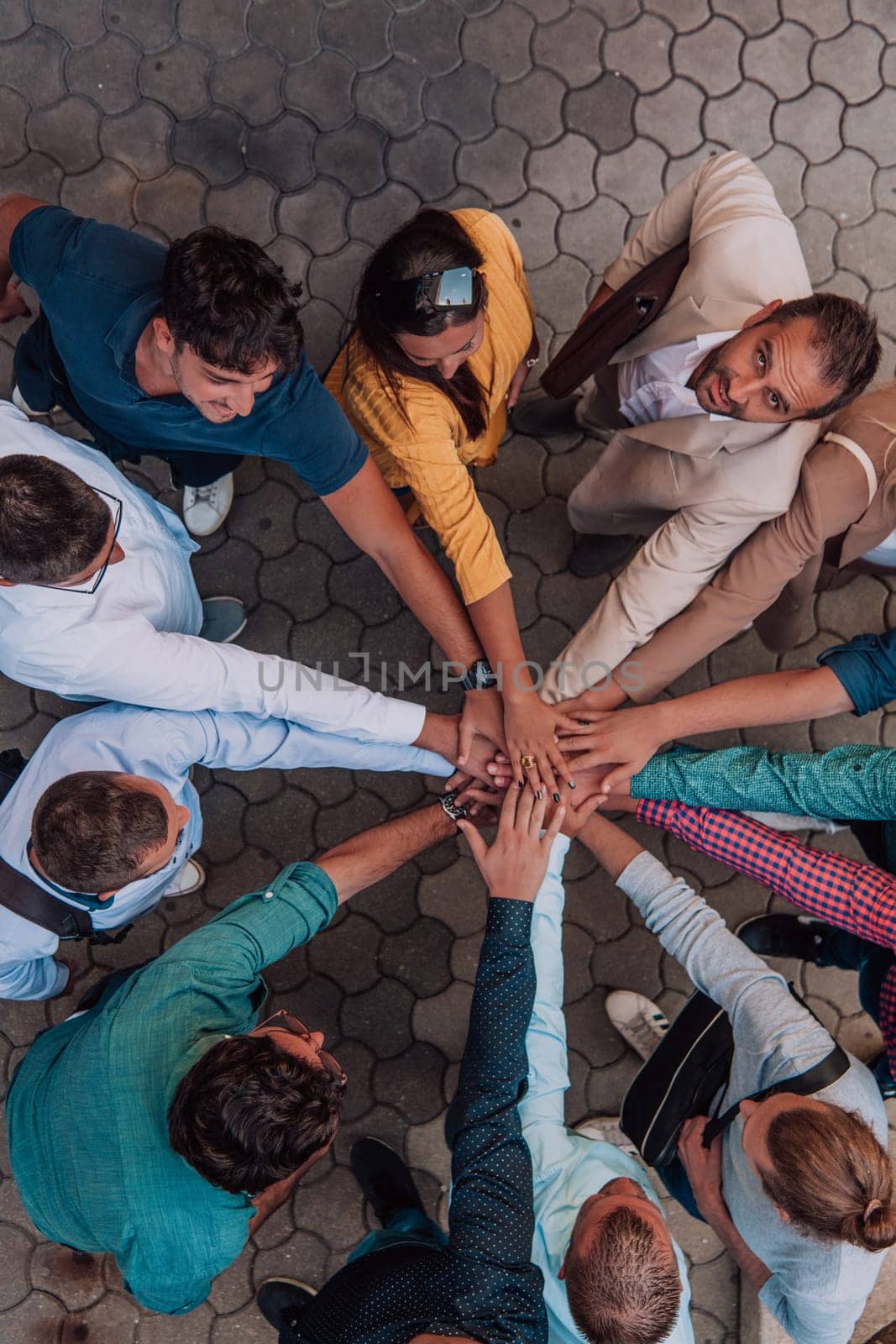 Top view photo of a group of business people and colleagues standing together holding hands, looking towards the camera, symbolizing unity and teamwork